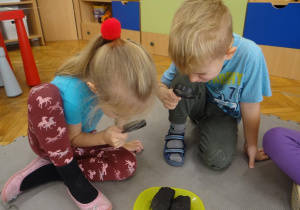 Dzieci obserwują węgiel przy pomocy lupy